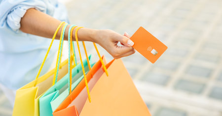 Millennial european woman with bags use credit card, enjoy shopping and free time in mall, close upの写真素材