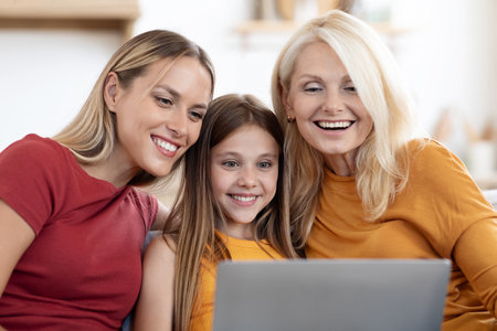 Happy family mother, daughter and grandmother using laptop at home