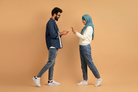 Muslim Dating Apps. Young Islamic Couple With Smartphones Walking Toward Each Other