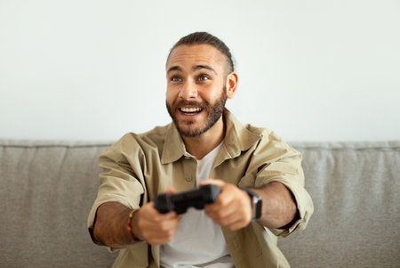 Happy young man playing video games at home, holding joystick