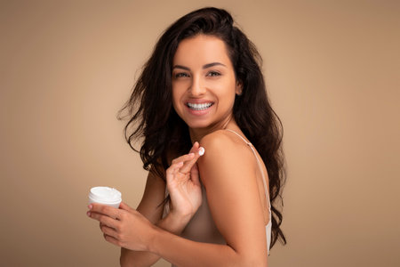 Happy beautiful young indian woman applying body cream on shoulderの写真素材