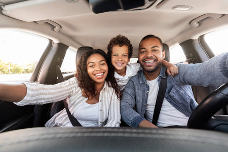 Cheerful african american family taking selfie, travelling together by carの写真素材
