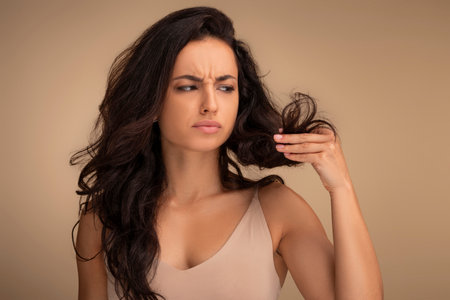 Stressed young brunette woman looking at unhealthy split ends hairの写真素材