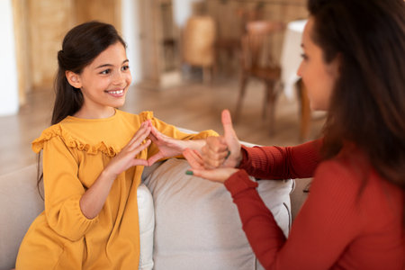 Girl Making Hand Gesture Using Sign Language With Tutor Indoorの写真素材