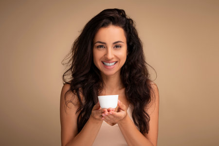 Organic cosmetic. Smiling woman holding jar of cream on palmsの写真素材