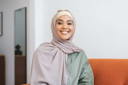 Portrait Of Happy Muslim Woman In Hijab Posing At Homeの写真素材