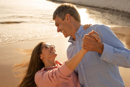 Cheerful middle aged couple dancing and having fun on the beach togetherの写真素材