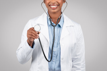 Black woman doctor attentively listening through stethoscopeの写真素材