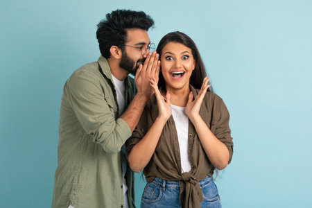 Middle eastern guy sharing secret with his excited pretty girlfriendの写真素材