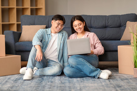 Asian Couple Using Laptop Online Service For Moving At Homeの写真素材