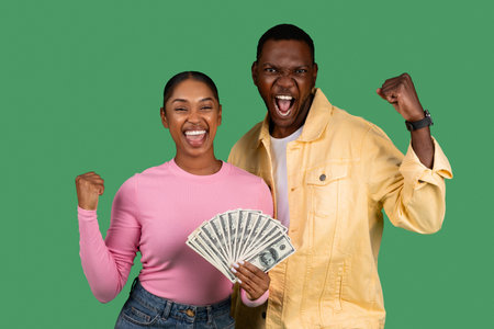 Overjoyed young African American couple holding bunch of moneyの写真素材