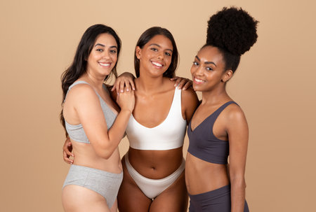 Three women, diverse and naturally beautiful, posing over beige backgroundの写真素材