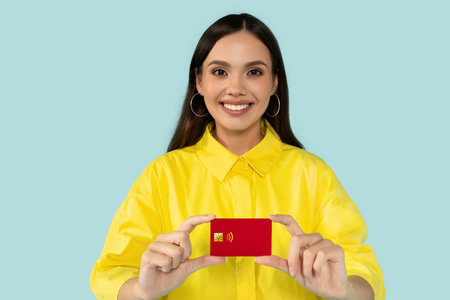 Cheerful young woman showing red credit card