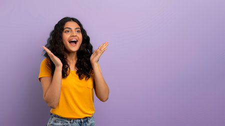 Excited hindu woman looking at blank space on purple backgroundの写真素材