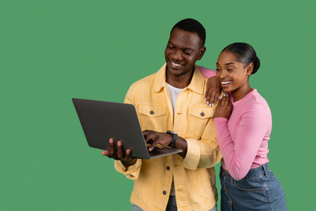 Loving african american man and woman using laptop on green