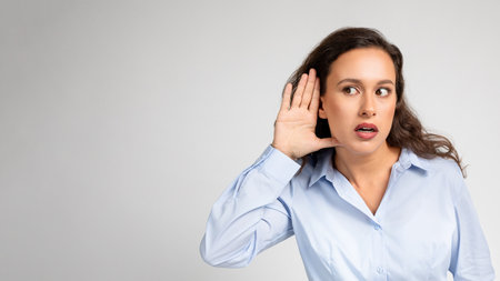 Young woman intrigued, listening intently, wide-eyed at some juicy gossip whisperedの写真素材