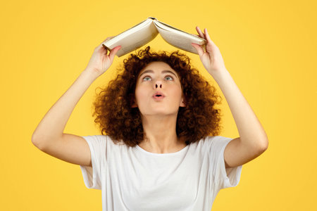 Shocked curiously caucasian young lady read book, enjoy spare time, isolated on yellow background