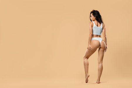 Perfect body shape. Woman posing in white underwear over beige studio backgroundの写真素材