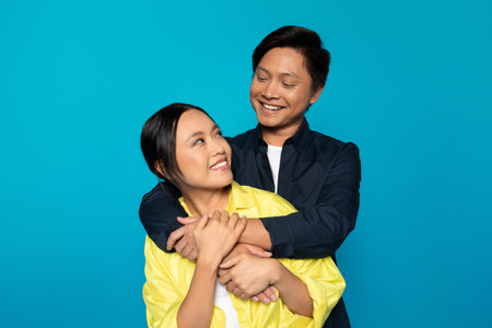 Smiling young japanese man in casual hugs wife, enjoy date at spare time togetherの写真素材