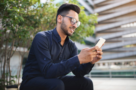 Arab entrepreneur man in glasses holding cellphone in urban setting
