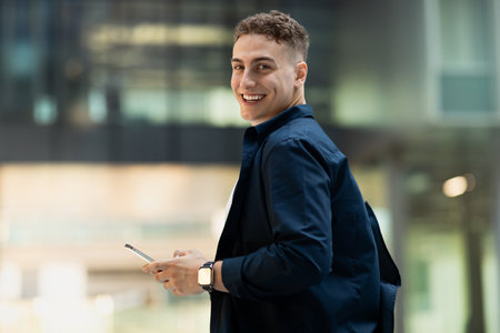 Smiling millennial caucasian man in casual, use phone in city, enjoy spare time with copy space
