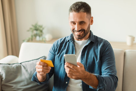 man making purchase using credit card on phone at homeの写真素材