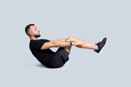 Serious handsome strong millennial european guy with beard in sportswear make exercises for abs