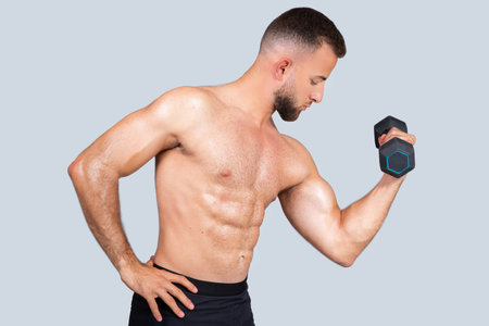 Concentrated calm sweat handsome strong muscular millennial caucasian guy with beard, naked torso make exercisesの写真素材