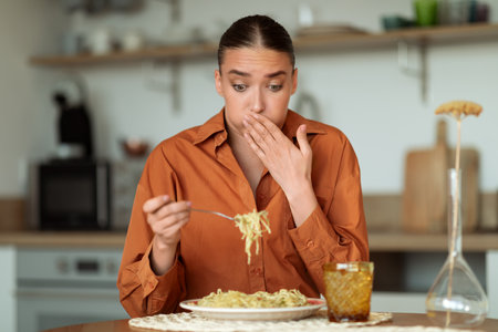 Woman in orange shirt, shocked by taste of noodlesの写真素材