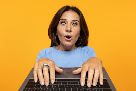 Positive shocked funny senior european lady typing on keyboard laptopの写真素材