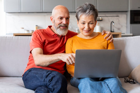 Happy Senior Couple Making Online Purchases While Relaxing With Laptop At Homeの写真素材