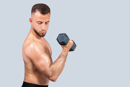 Serious sweat strong muscular millennial european man athlete with beard, naked torso make exercises with dumbbellの写真素材