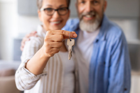 Real Estate Concept. Happy Senior Couple Holding Home Keys, Showing To Cameraの写真素材