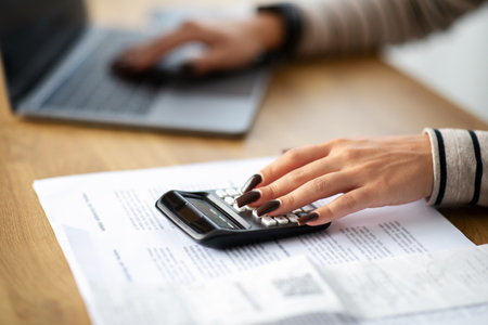 Young arab woman manager work at computer, calculator, pay bill taxes at table, cropped