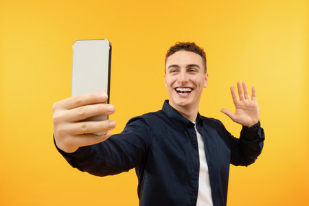 Positive guy waving and smiling at smartphone screen