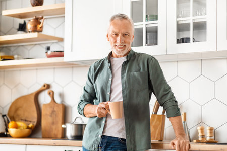 Smiling Senior Man Drinking Coffee In Kitchen Interiorの写真素材