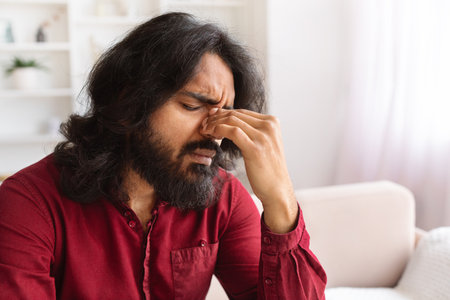 Unhappy young indian man experiencing problems, have headacheの写真素材