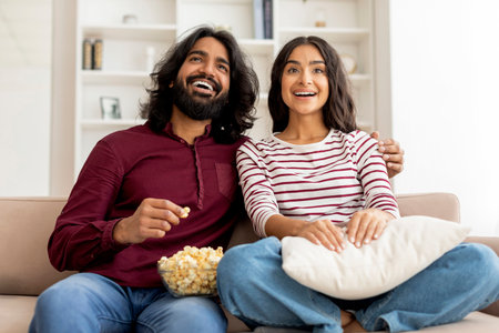 Positive smiling lovers sitting on couch in cozy living roomの写真素材