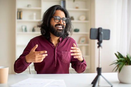 Young Indian Male Blogger Recording Video At Home With Smartphone On Tripod