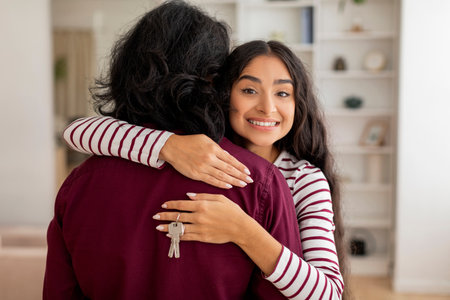 Happy young indian woman hugging husband, holding key from apartmentの写真素材
