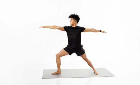 fitness instructor guy demonstrating yoga warrior pose over white backgroundの写真素材