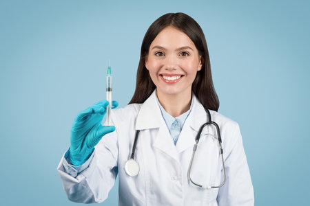 Cheerful woman doctor in white coat with syringeの写真素材