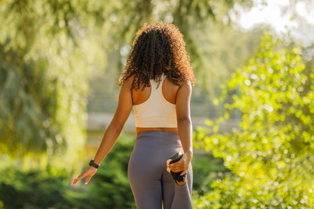 Back view of young sporty woman stretches her leg outdoorsの写真素材