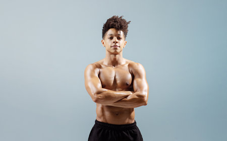 young sportsman standing shirtless with perfect torso arms crossed, studioの写真素材