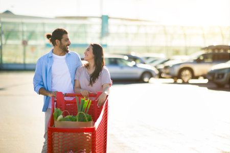 Loving couple with shopping cart in sunlight, copy spaceの写真素材