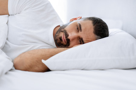 Middle aged bearded man struggles with insomnia lying in bedroomの写真素材