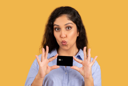 Happy latin young brunette lady show credit card, has fun, recommend saleの写真素材