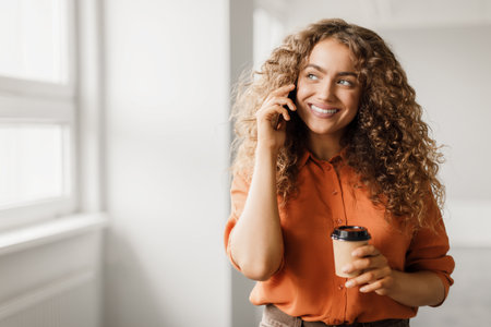 Joyful woman on call with coffee cupの写真素材