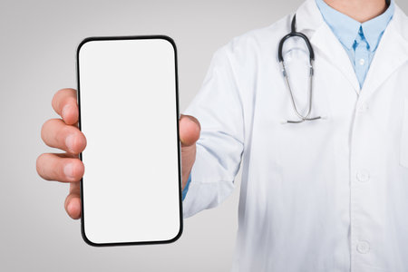 Male doctor holding a smartphone with a blank screenの写真素材