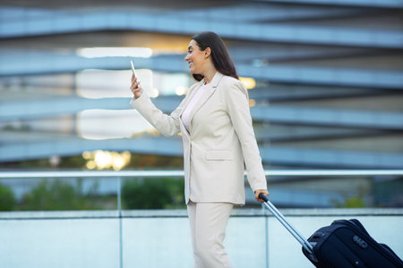 Arabic businesswoman on business trip using her smartphone walking outsideの写真素材